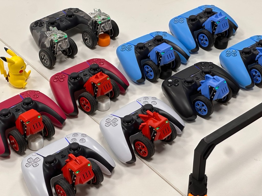 A fleet of small self-balancing Robomates robots next to game controllers